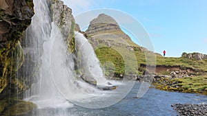 Kirkjufellsfoss waterfall near the Kirkjufell mountain, unrecognisable woman