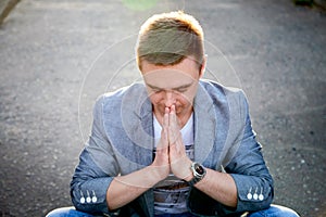 Kirov, Russia - September 04, 2019: Portrait of a handsome fun man sitting on the asphalt for pray or yoga on a city street