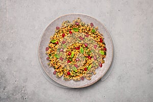 Kisir on gray plate on concrete table top. Turkish cuisine bulgur and parsley salad dish with pomegranate. Turkish food and meal photo