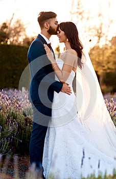 Kiss, bride and couple at sunset on wedding, celebration and commitment with love and hope. Marriage, fashion and people