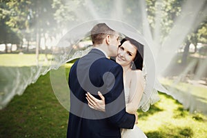 Kiss of bride and groom under bride's veil