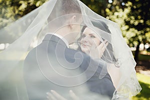 Kiss of bride and groom under transparent veil