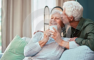 Kiss, coffee and senior couple laughing, talking and smile during retirement in the living room of their house. Relax