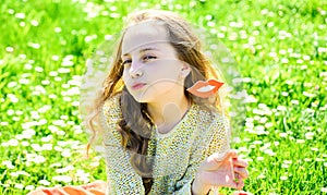 Kiss concept. Girl on kissing face spend leisure outdoors. Girl sits on grass at grassplot, green background. Child photo