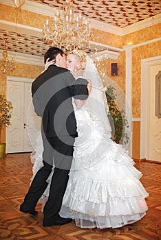 Kiss and dance young bride and groom in banqueting hall photo