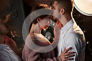 A kiss on the forehead. Closeness of the guy and girl in luxury wear that dancing and flirting. Gorgeous reflection from the side