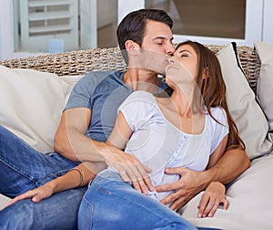 Kiss, love and couple relaxing on sofa for bonding in living room at apartment together. Happy, resting and young man