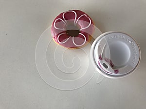 Kiss mark on plastic cup of coffee and pink flower doughnut