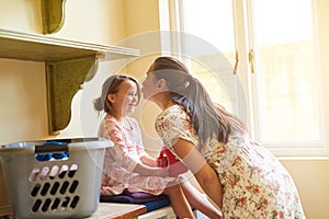 Kiss, mother and girl with clothes for laundry for washing in house, apartment or home for housekeeping and cleanliness