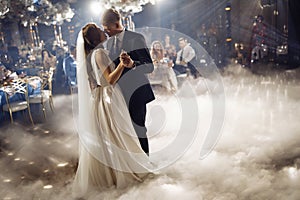 Kiss of newlyweds on first wedding dance and. Just married couple dancing in darkness. Groom holds bride& x27;s hand
