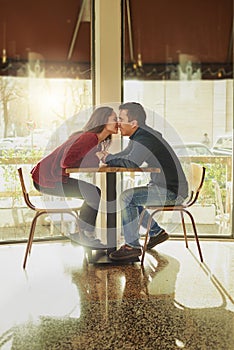 Kisses dont wait on anybody. a young man and woman on a romantic date at a coffee shop.