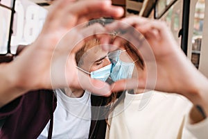 Kissing couple doing heart shape with protective mask