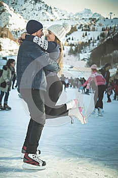 Kissing couple, girls and boy ice skating outdoor at rink