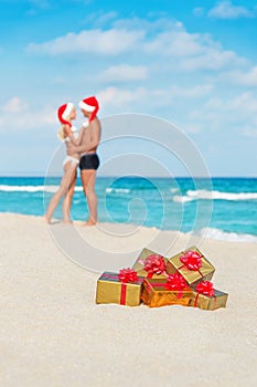 Kissing couple in santa hats at sea beach