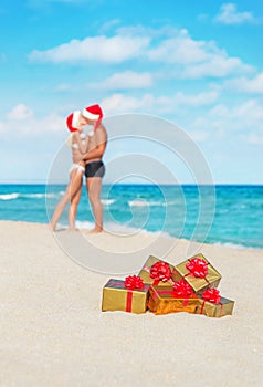 Kissing couple in santa hats at sea beach
