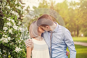 Kissing couple, young man and woman outdoor in spring sunny park