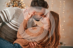 Kissing each other. Lovely young couple are celebrating New Year at home