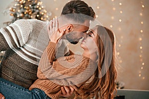 Kissing each other. Lovely young couple are celebrating New Year at home
