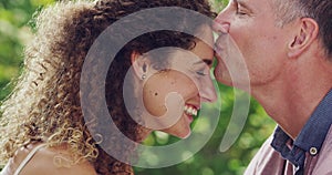 Kissing, happy and mature caucasian couple enjoying a day together outdoors. A closeup of laughing, loving and