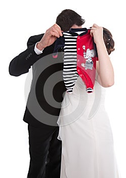 Kissing wedding couple with baby clothes: pregnancy and marriage