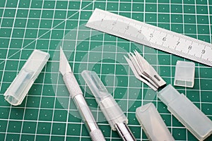 Kit of scalpels, blades and ruler on cutting mat before