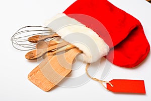 Kitchen accessories or kit of kitchenware packed in big red sock, white background. Christmas menu concept. Kitchenware