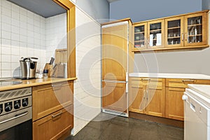 kitchen with amber cherry wood cabinets, wood countertops and built-in appliances, white tiles
