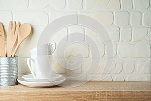 Kitchen background with dishware, utensils, cup and plate on wooden shelf