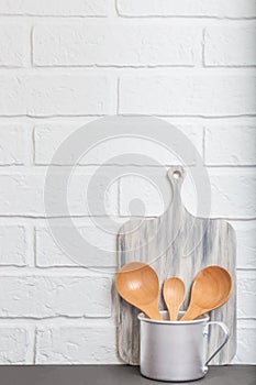 Kitchen background loft style. Kitchen utensils, dishes, wooden spoons in an aluminum mug on the background of a white