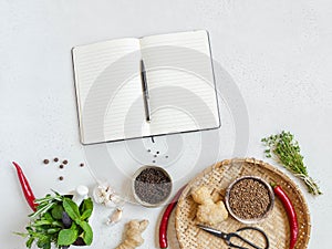 Kitchen background with open cookbook for recipes and various spices and herbs on light background. Top view. Copy space