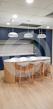 kitchen, blue and grey cabinets, orange pendant lights, polished concrete floors, hanging plant baskets, tables and chairs