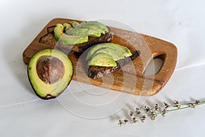 On the kitchen board half an avocado and slices on bread, avocado sandwich