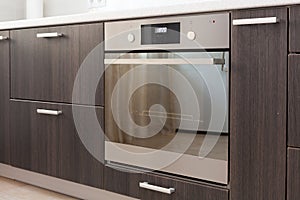 Kitchen cabinets with metal handles and built-in electric oven. photo