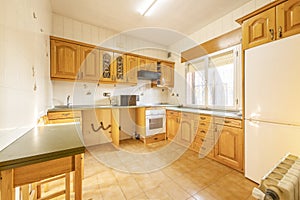 Kitchen with Castilian-style wooden furniture with a table with a gray top and integrated appliances