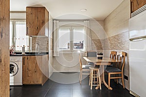 A kitchen with chestnut wood cabinets, black synthetic stone countertops, integrated appliances