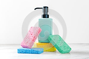 Kitchen cleaning and washing sponges with dish soap bottle on white marble kitchen table