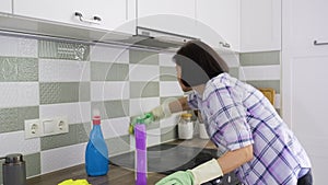 Kitchen cleaning, woman washing ceramic wall tiles over glass ceramic hob