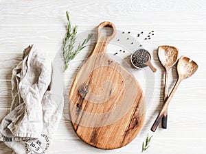 Kitchen cooking flat lay. Spices, wood spoons and wood cutting board for placing your text on a light wood background. Top view.