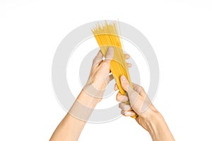 The kitchen and the cooking theme: man's hand holding a stack of raw spaghetti on an isolated white background in studio