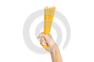 The kitchen and the cooking theme: man's hand holding a stack of raw spaghetti on an isolated white background in studio
