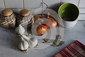 Kitchen corner with white garlic cloves, golden onions, pots and tea towel