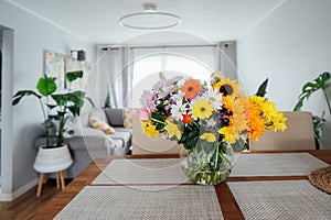 Kitchen counter table with focus on vase with huge multicolor various flower bouquet with blurred background of modern