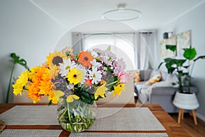 Kitchen counter table with focus on vase with huge multicolor various flower bouquet with blurred background of modern