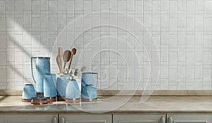 Kitchen counter with various jars, carafe and wooden spoon sets on it with alternating white tiled wall, under morning sunshine,