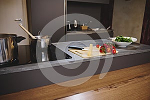 Kitchen countertop with ingredients in a modern minimalist gray home kitchen interior. On the cutting board there is a