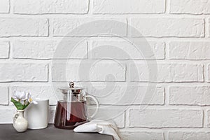 Kitchen cozy light background with copy space in loft style. Glass teapot with tea on the table. Tea break