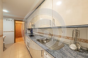 Kitchen with cream-colored wooden cabinets with blue countertops and white built-in appliances