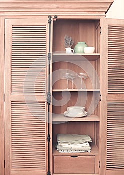 Kitchen cupboard with disheslike plates, tableclothes and glasses