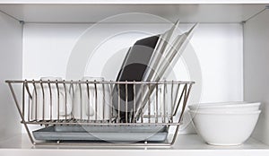 Kitchen cupboard with a lattice for dishes, with a white and black plate, cups, and a drip tray