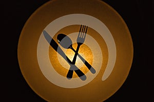 Kitchen cutlery silhouetted by a golden circular glowing light